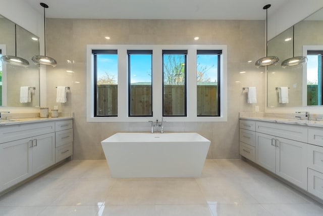 full bath featuring tile walls, a freestanding tub, plenty of natural light, and tile patterned floors