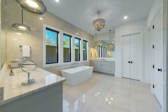 bathroom with an inviting chandelier, vanity, tile walls, and a washtub