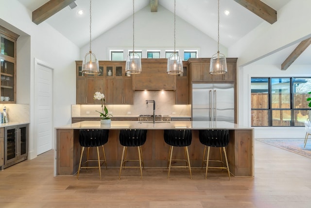 kitchen with light wood finished floors, beverage cooler, tasteful backsplash, and built in fridge