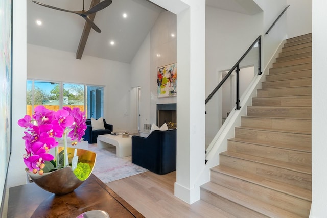 living room featuring beam ceiling, high vaulted ceiling, light hardwood / wood-style floors, and ceiling fan