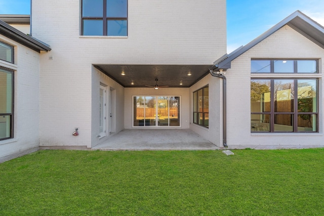 rear view of property featuring a patio area, a lawn, and brick siding