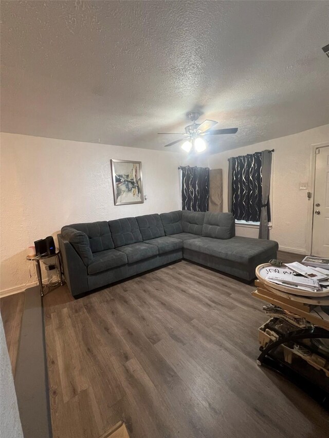 living room with ceiling fan, dark hardwood / wood-style flooring, and a textured ceiling