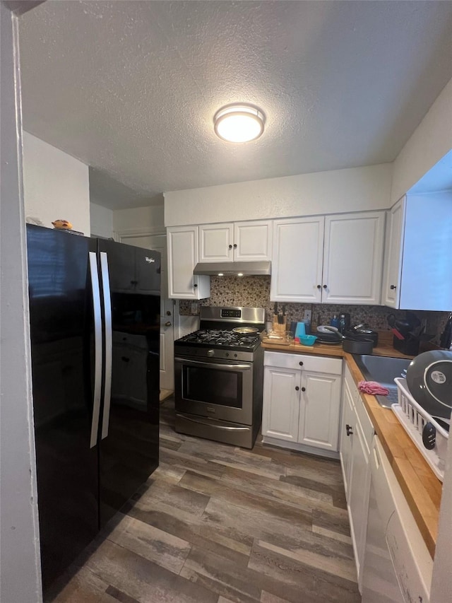 kitchen with backsplash, black fridge, gas stove, hardwood / wood-style floors, and white cabinetry