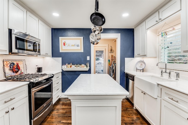 kitchen with a center island, white cabinets, dark hardwood / wood-style floors, appliances with stainless steel finishes, and washer / dryer