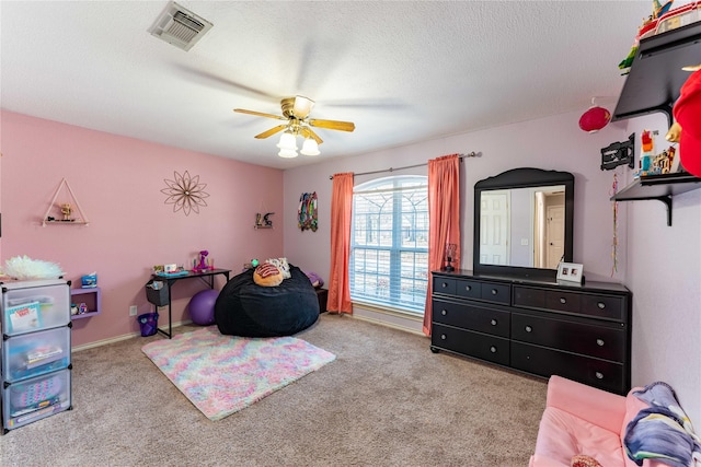 carpeted bedroom with ceiling fan and a textured ceiling