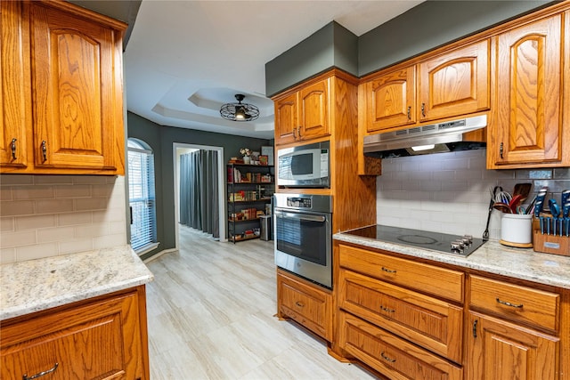 kitchen with built in microwave, oven, decorative backsplash, black electric stovetop, and light stone counters