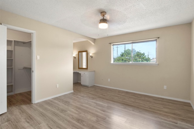 interior space with a walk in closet, ceiling fan, a closet, and light wood-type flooring