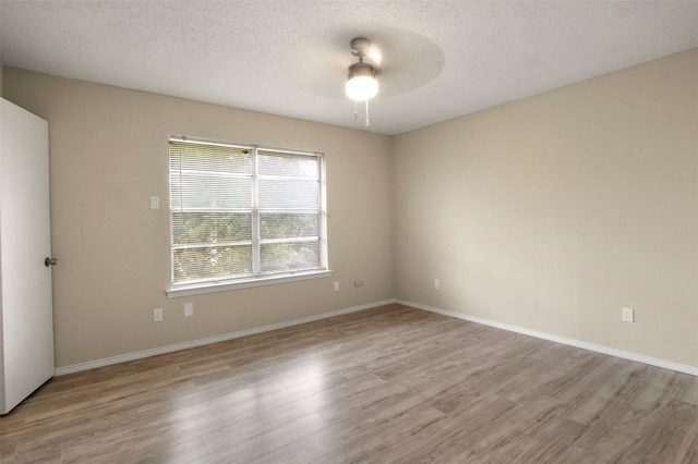 spare room featuring ceiling fan, plenty of natural light, a textured ceiling, and light wood-type flooring