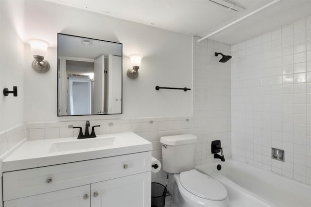 full bathroom with tiled shower / bath, vanity, toilet, and tile walls