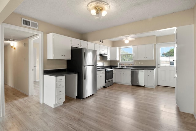 kitchen with white cabinetry, light wood-type flooring, a textured ceiling, and appliances with stainless steel finishes