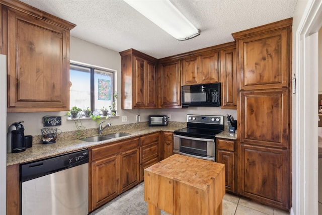 kitchen with appliances with stainless steel finishes, a textured ceiling, sink, light tile patterned floors, and butcher block countertops