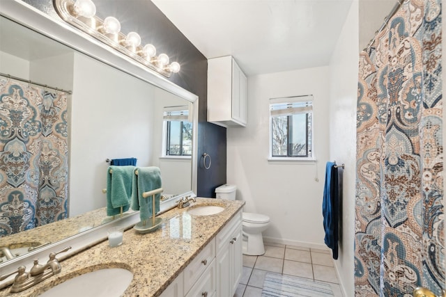 bathroom with tile patterned flooring, vanity, toilet, and a healthy amount of sunlight