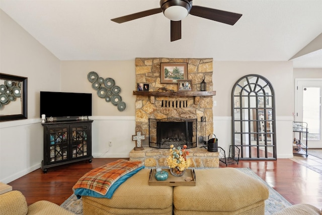 living room with a stone fireplace, dark wood-type flooring, and vaulted ceiling