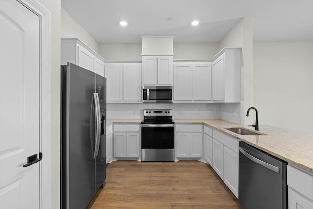 kitchen featuring sink, appliances with stainless steel finishes, tasteful backsplash, light stone counters, and white cabinetry