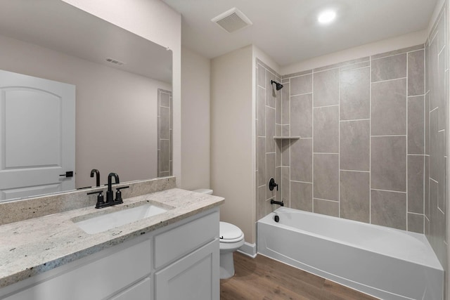 full bathroom with vanity, toilet, wood-type flooring, and tiled shower / bath