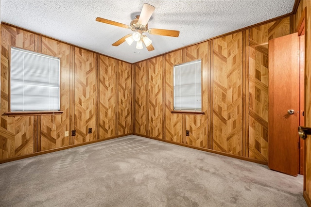 empty room with ceiling fan, light colored carpet, a textured ceiling, and ornamental molding