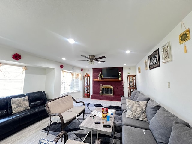 living room with a fireplace, light hardwood / wood-style flooring, and ceiling fan