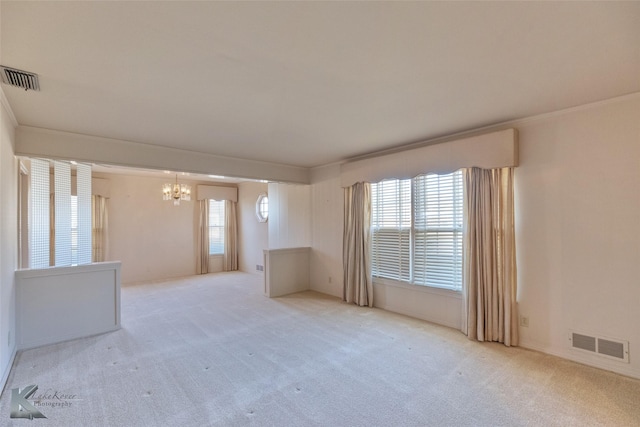 empty room featuring light carpet, a chandelier, and ornamental molding