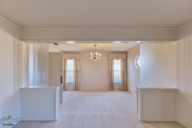 spare room featuring light colored carpet, ornamental molding, and an inviting chandelier