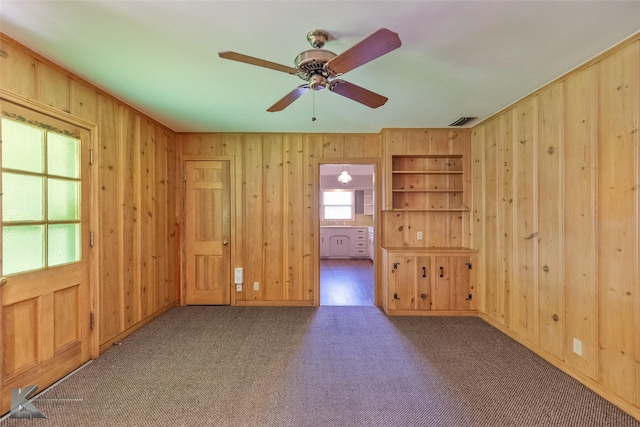 unfurnished room featuring ceiling fan, carpet floors, and built in shelves