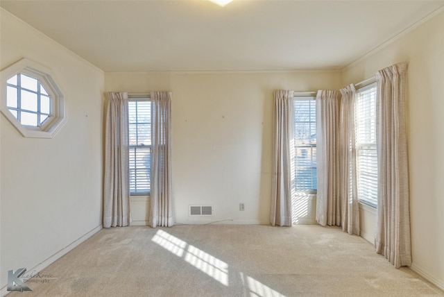 unfurnished room featuring a healthy amount of sunlight, light colored carpet, and ornamental molding