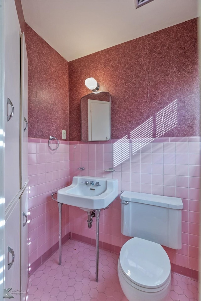 bathroom featuring tile patterned flooring, toilet, and tile walls