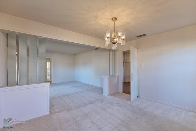 spare room featuring light carpet and an inviting chandelier