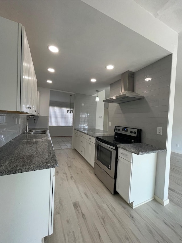 kitchen featuring stainless steel range with electric stovetop, sink, white cabinetry, and wall chimney exhaust hood