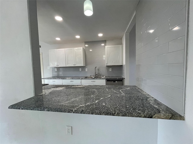 kitchen featuring backsplash, white cabinetry, sink, and dark stone counters