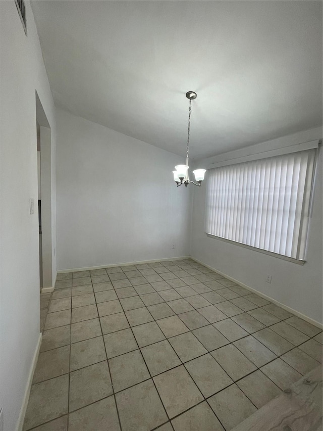 empty room featuring a notable chandelier and light tile patterned floors