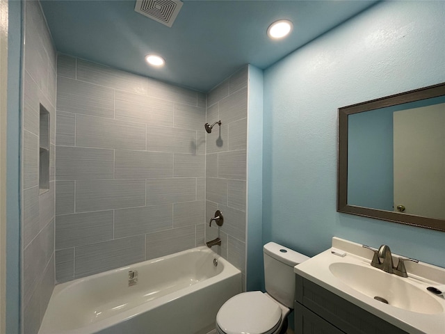 full bathroom featuring vanity, tiled shower / bath combo, and toilet