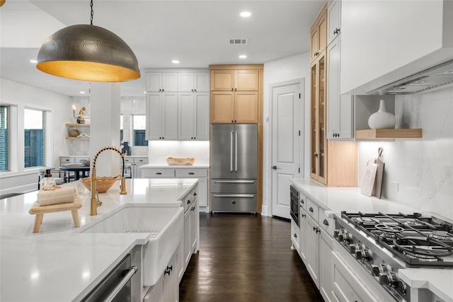 kitchen with light stone counters, stainless steel appliances, decorative light fixtures, and light brown cabinetry