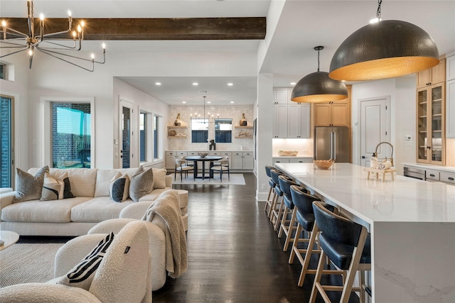 living room with beamed ceiling, a notable chandelier, and dark hardwood / wood-style flooring