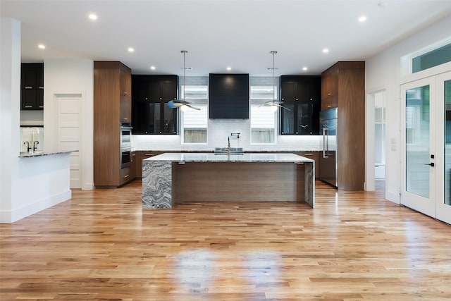 kitchen featuring light stone countertops, french doors, hanging light fixtures, and appliances with stainless steel finishes