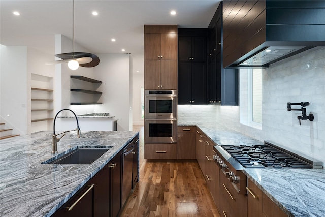 kitchen featuring light stone countertops, sink, wall chimney exhaust hood, dark hardwood / wood-style flooring, and appliances with stainless steel finishes