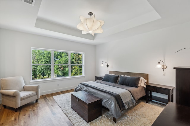 bedroom featuring a tray ceiling and light hardwood / wood-style floors