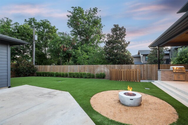 yard at dusk with a patio, an outdoor kitchen, and a fire pit