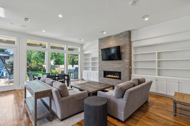 living room featuring ceiling fan, a fireplace, and light hardwood / wood-style flooring