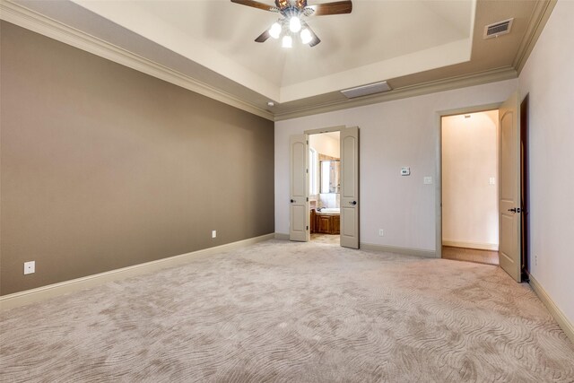 unfurnished bedroom featuring ceiling fan, light carpet, connected bathroom, and a tray ceiling