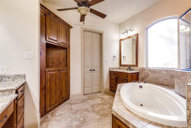 bathroom featuring vanity, a relaxing tiled tub, and ceiling fan