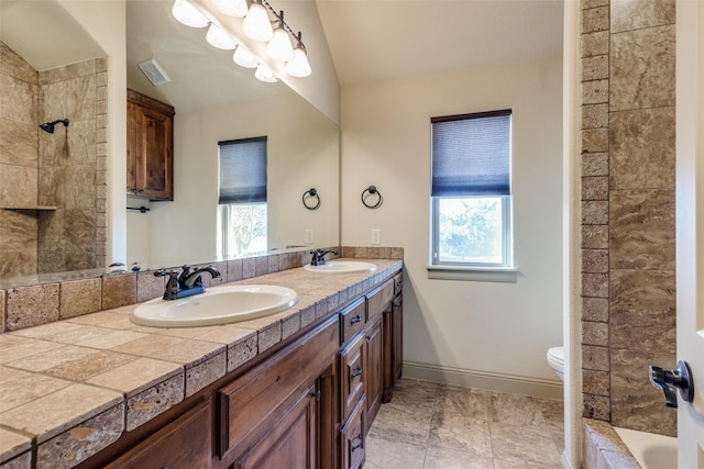 bathroom featuring a wealth of natural light, vanity, lofted ceiling, and toilet