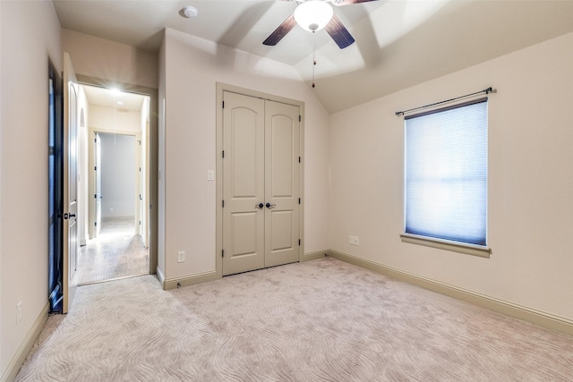 unfurnished bedroom with a closet, vaulted ceiling, ceiling fan, and light colored carpet