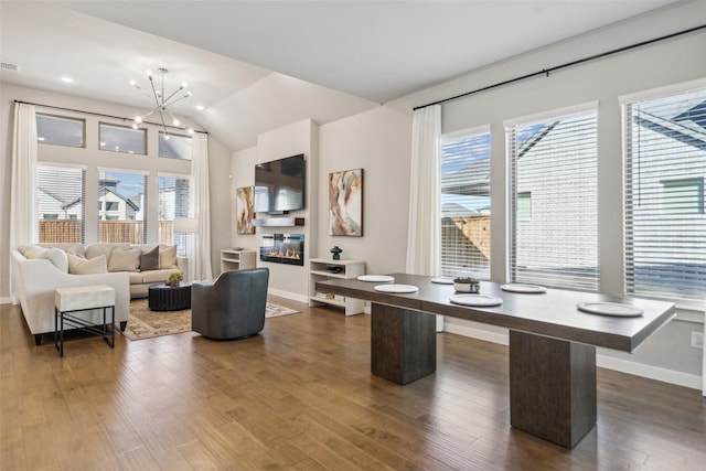 office area with lofted ceiling, a healthy amount of sunlight, dark hardwood / wood-style floors, and a notable chandelier