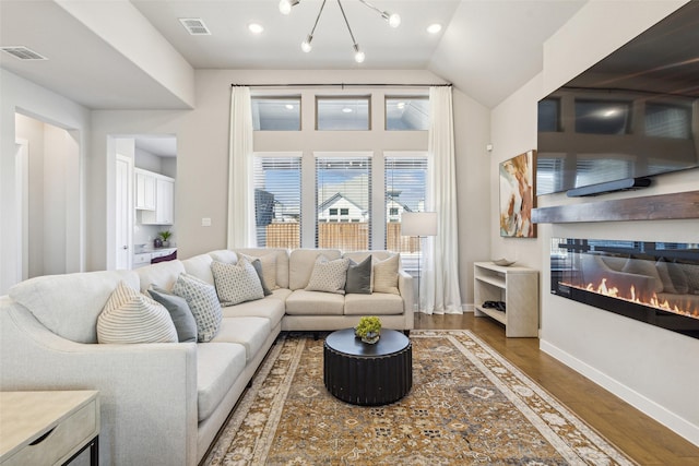 living room with wood-type flooring, lofted ceiling, and a notable chandelier