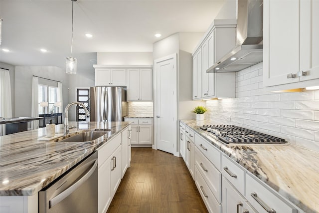 kitchen featuring white cabinets, sink, wall chimney exhaust hood, light stone countertops, and appliances with stainless steel finishes