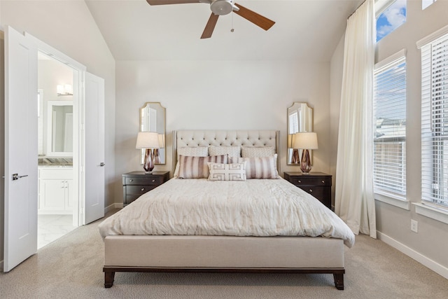 carpeted bedroom featuring ceiling fan, vaulted ceiling, multiple windows, and ensuite bath