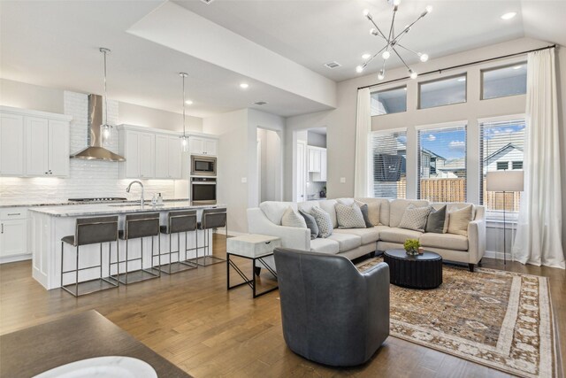 living room with an inviting chandelier, dark wood-type flooring, and sink