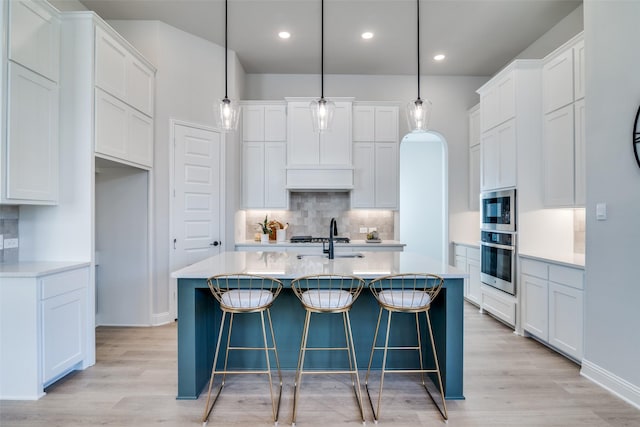 kitchen featuring sink, decorative light fixtures, a kitchen island with sink, white cabinets, and appliances with stainless steel finishes