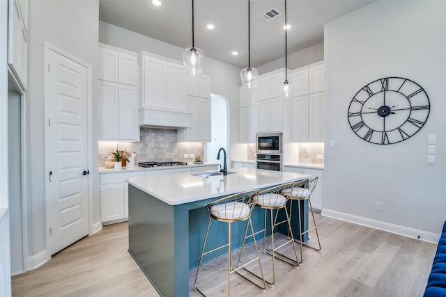 kitchen featuring white cabinets, a center island with sink, and sink