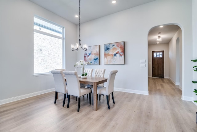 dining space featuring light wood-type flooring and a notable chandelier